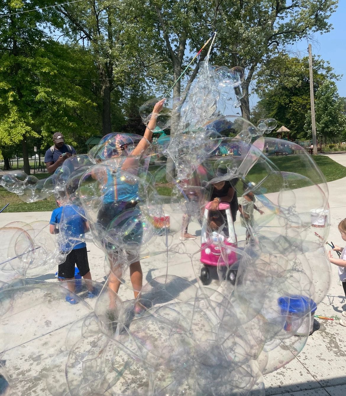 Children and adults playing with giant bubbles in a community park