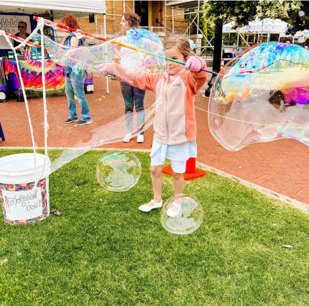 Child making giant colorful bubbles outdoors